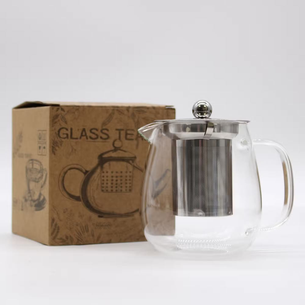 Clear glass teapot with metal lid next to a cardboard box labeled 'Glass Teapot' on a white background
