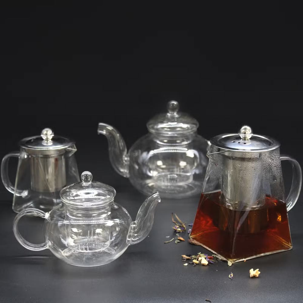 Set of glass teapots with metal infusers on a dark background