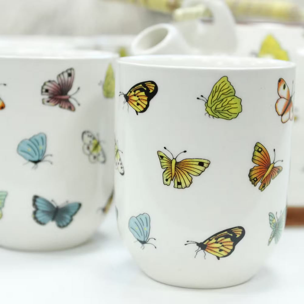 White ceramic mug with colorful butterfly designs on a white background