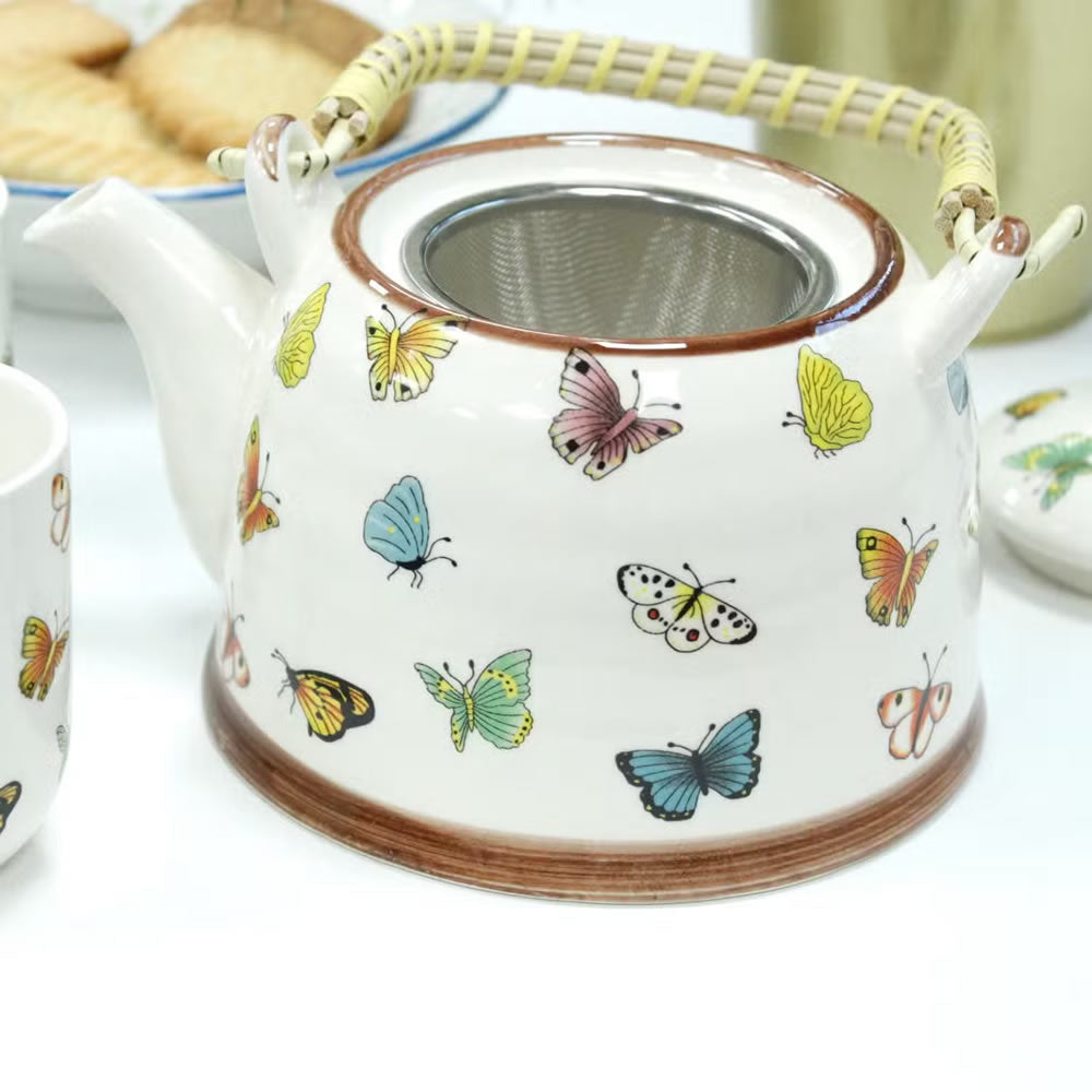 Teapot with butterfly design on a white surface
