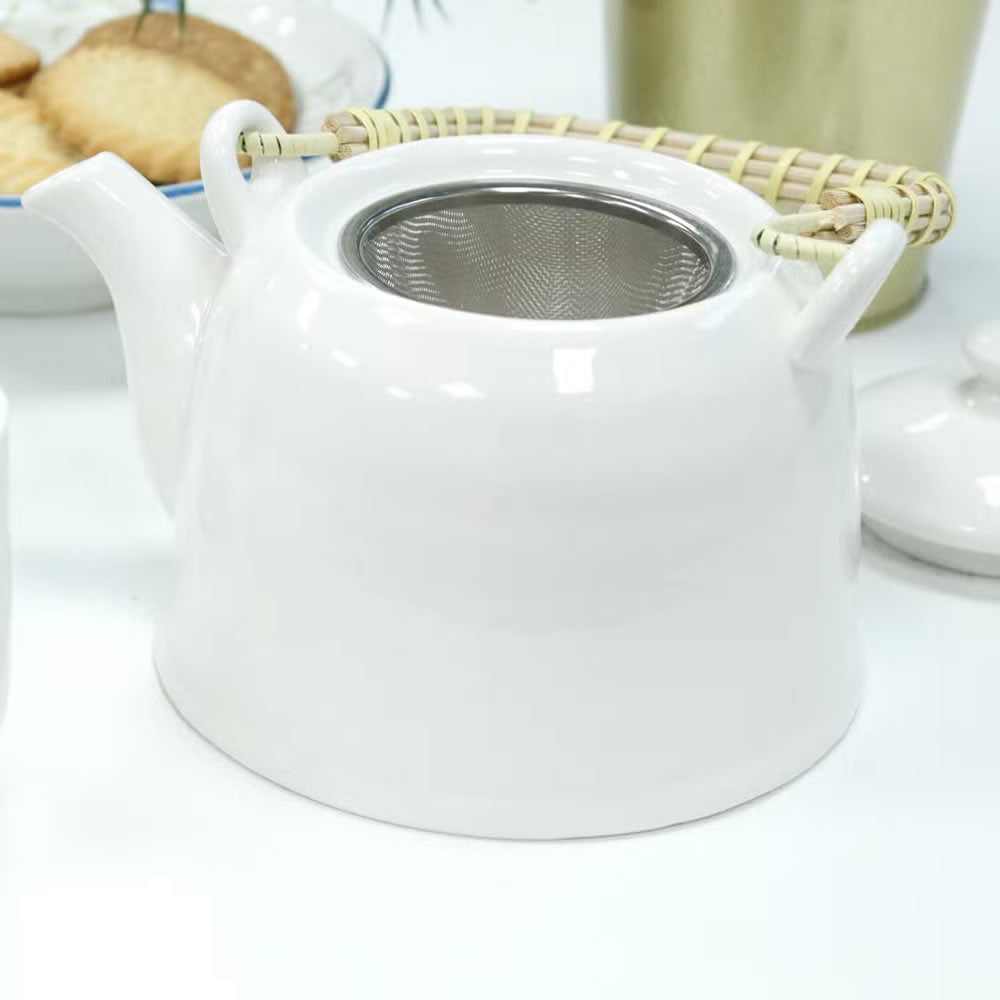 White ceramic teapot with a metal filter on a white background