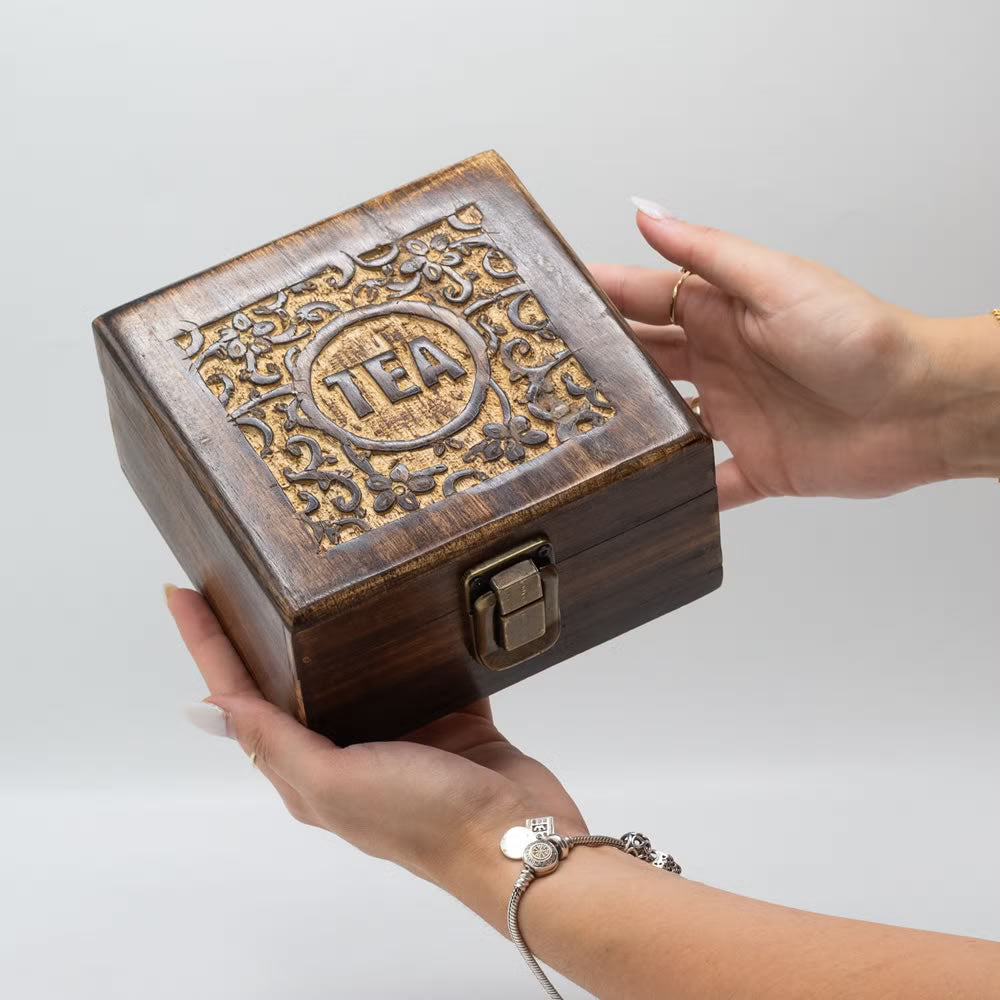 Wooden tea box with decorative top held by a hand on a light gray background