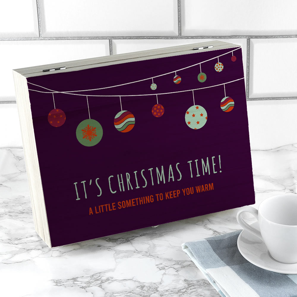 Purple box with Christmas-themed design and text on a marble surface with a cup and saucer.