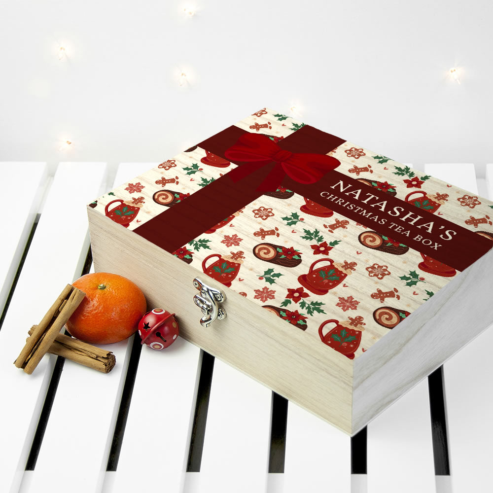 Decorative tea box with a red ribbon, featuring Christmas-themed designs, on a white surface.