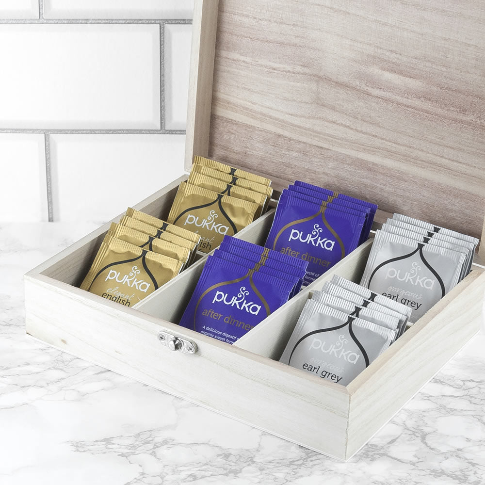 Pukka tea packets in a wooden box on a marble surface