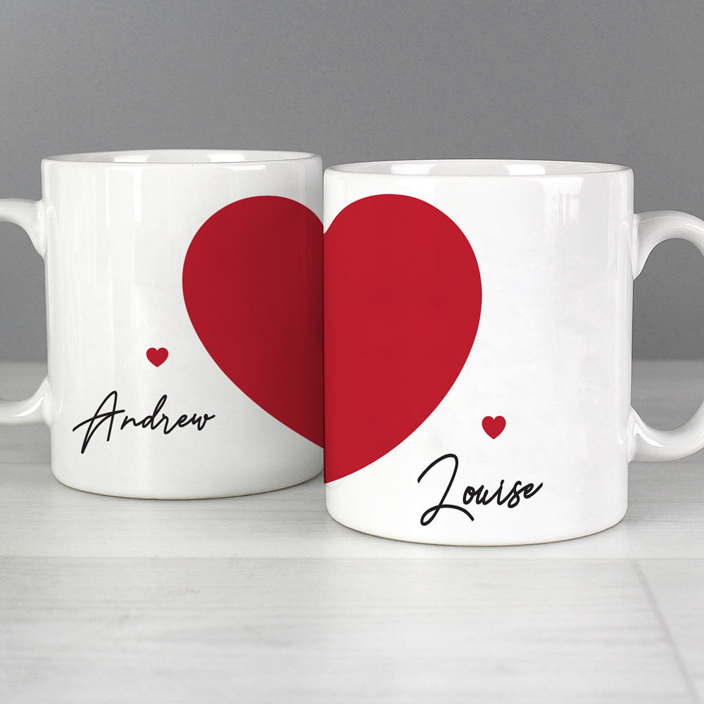 Two white mugs with red hearts and names 'Andrew' and 'Louise' on a gray background