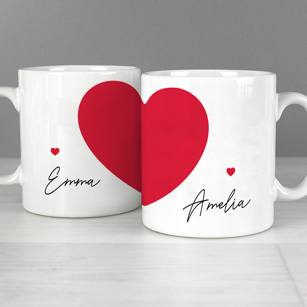 Two white mugs with red hearts and names 'Emma' and 'Amelia' on a gray background