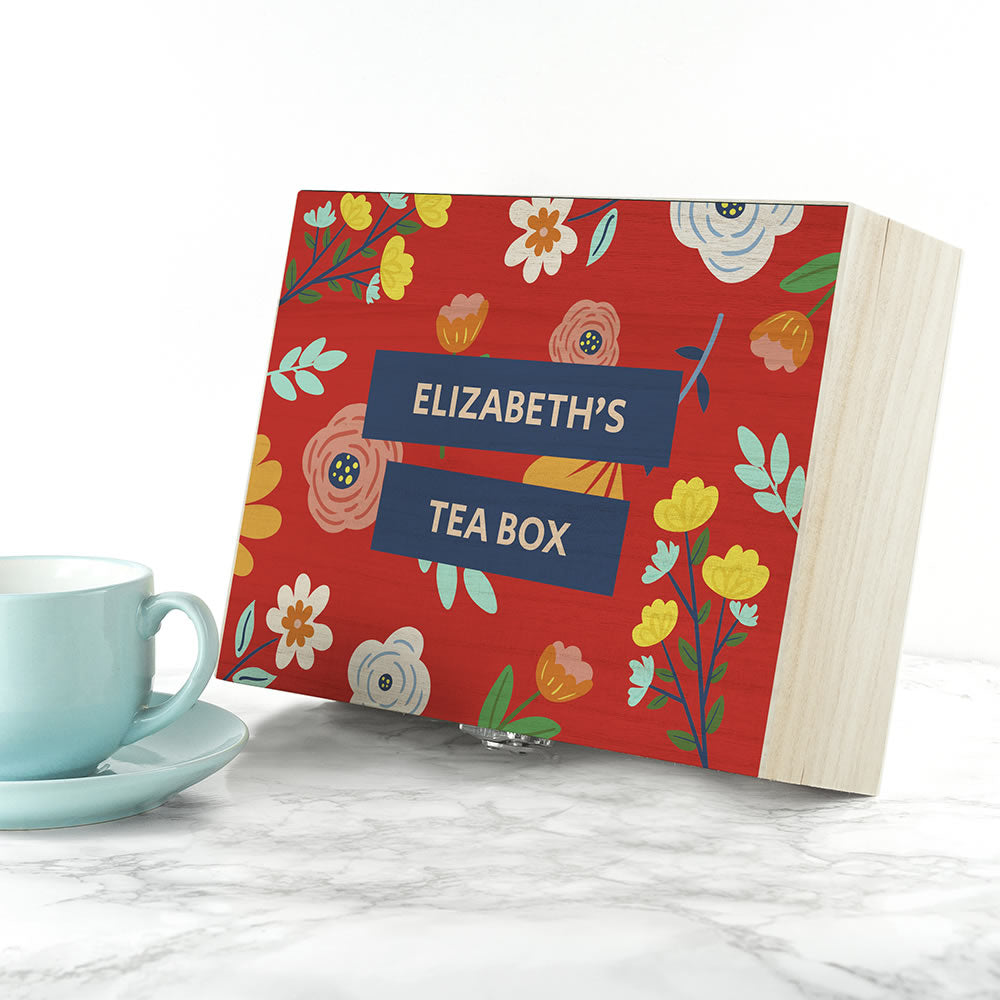 Floral-patterned tea box with 'Elizabeth's Tea Box' label next to a blue mug on a white surface