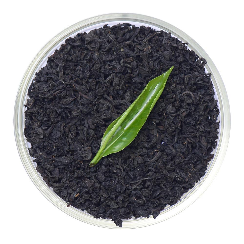 Pure Ceylon English Breakfast Black Tea (FBOP) leaves in a clear container with a green leaf on a white background -  www.ceylonteabox.com