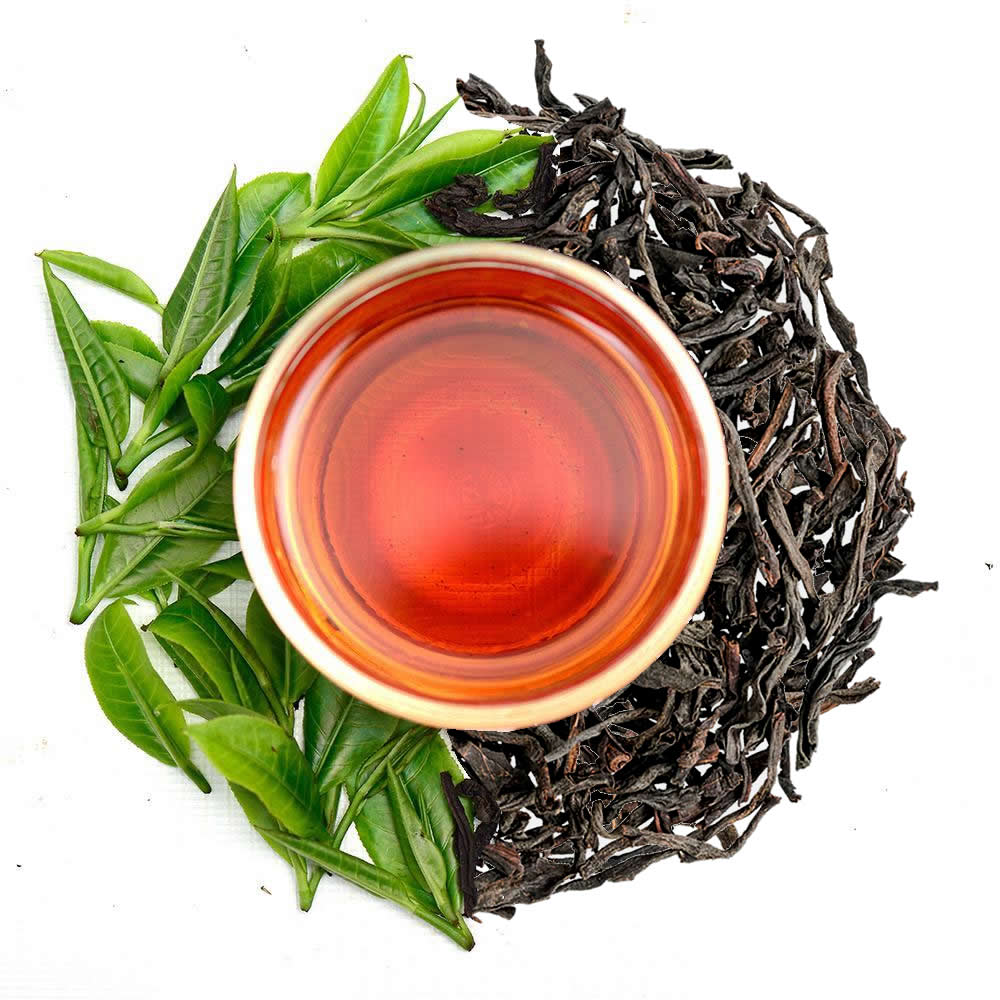 Pure Ceylon Orange Pekoe (OP) Black Tea cup with red liquid, surrounded by green tea leaves and black tea leaves - www.ceylonteabox.com 