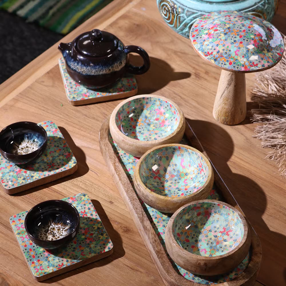 Tea set with teapot, bowls, and coasters on a wooden table
