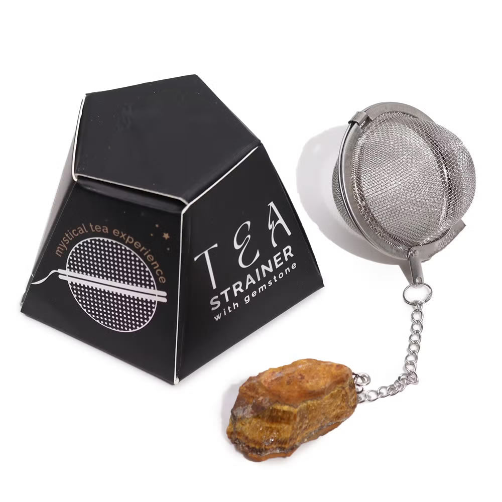Tea strainer with gemstone next to its packaging on a white background