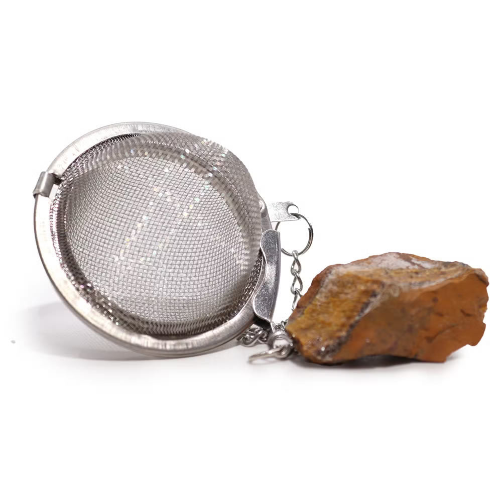 Metallic tea ball infuser with a stone on a white background