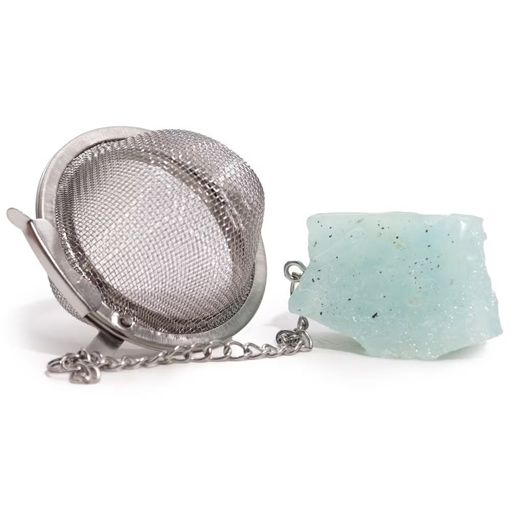 Metallic tea ball infuser with a ceramic holder on a white background