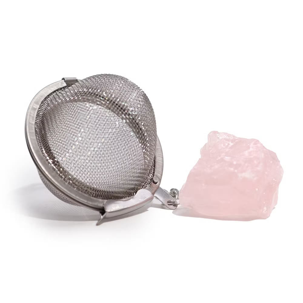 Metallic tea infuser with a pink stone on a white background